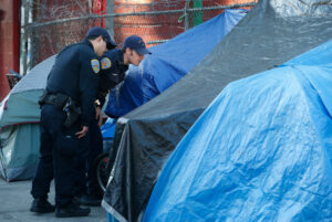 Police officers order a homeless encampment at 14th and Mission streets to move on before a Public Works crew can clean and disinfect the sidewalk in San Francisco, Calif. on Tuesday, March 14, 2017. (Photo By Paul Chinn/The San Francisco Chronicle via Getty Images)