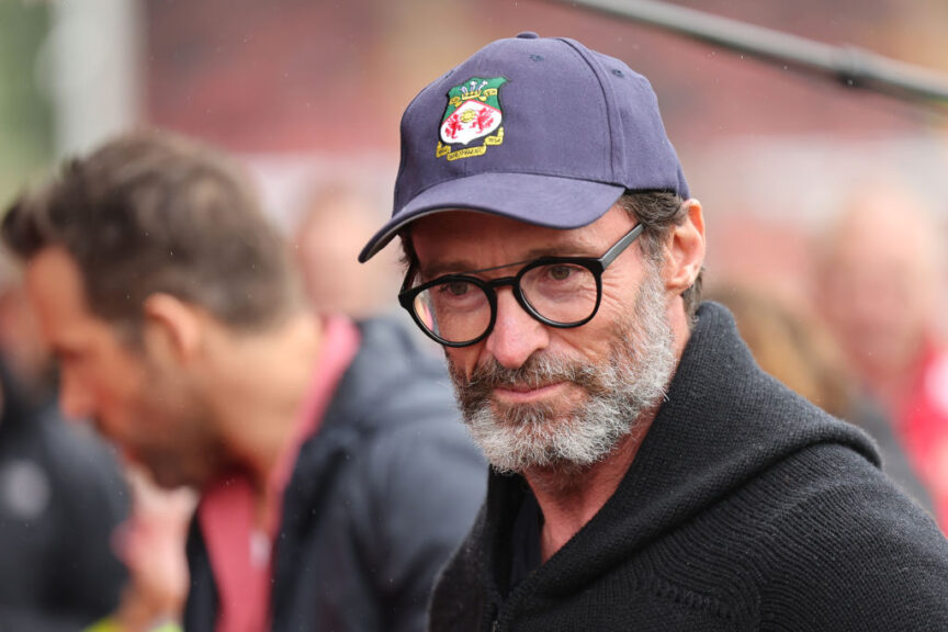 WREXHAM, WALES - AUGUST 5: Actor Hugh Jackman, a guest of owner Ryan Reynolds the co-owner of Wrexham wears a Wrexham hat whilst greeting fans prior to the Sky Bet League Two match between Wrexham and Milton Keynes Dons at Racecourse Ground on August 5, 2023 in Wrexham, Wales. (Photo by Matthew Ashton - AMA/Getty Images)